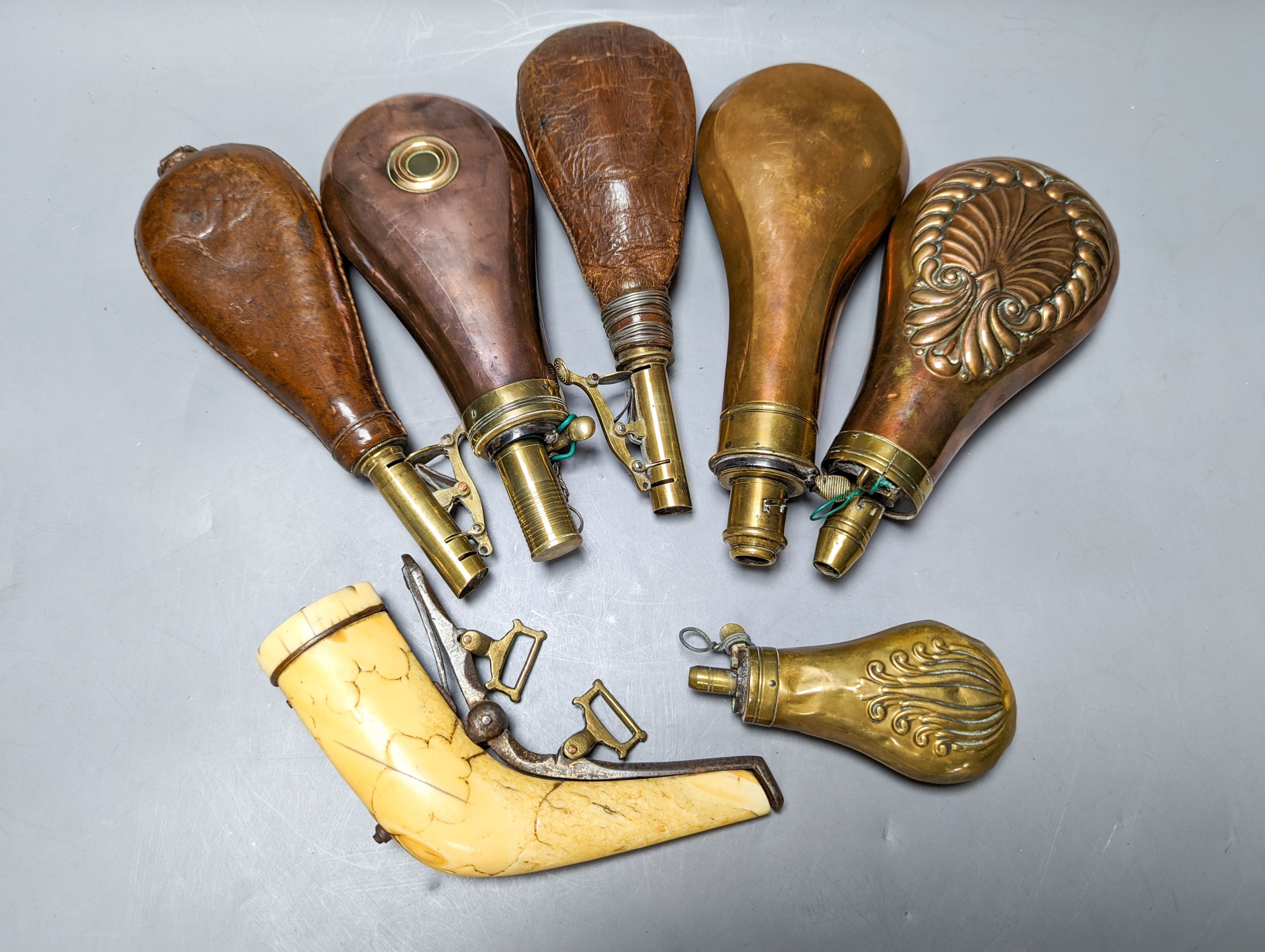 Six powder/shot flasks, 4 copper and brass, 2 leather and brass, together with a carved powder horn (7)